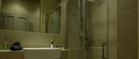 A modern bathroom with a glass-enclosed shower, a sink with a towel, and a mirror.