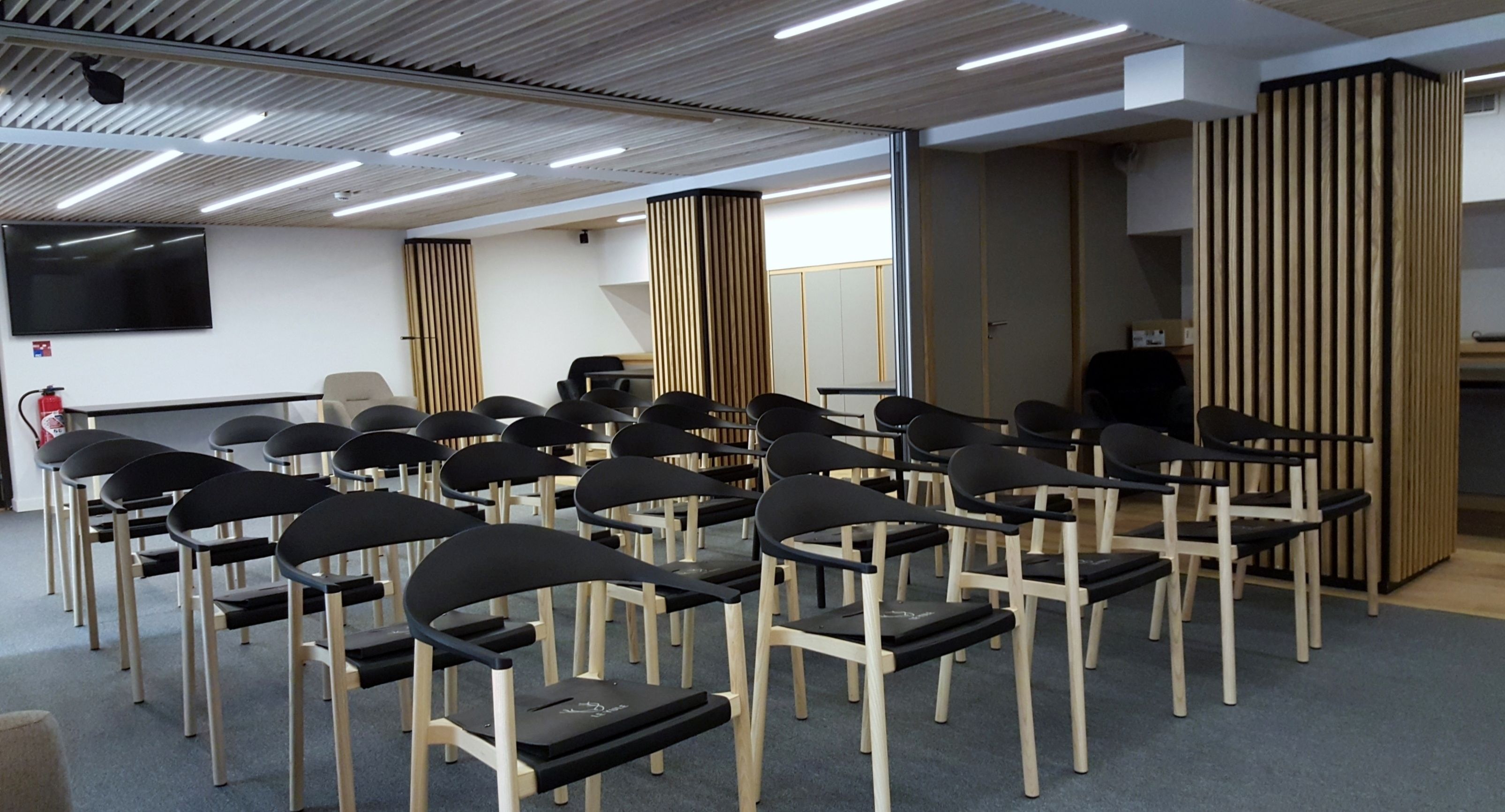 A conference room with rows of chairs, a large screen, and a wooden partition.