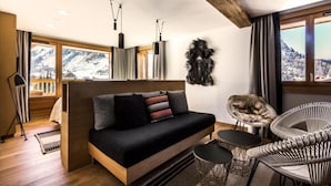 A modern living room with a sofa, two chairs, a view of snow-covered mountains, and a large window. - Le Yule Hotel & Spa (Val-d'Isere)