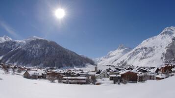Un villaggio innevato con edifici tradizionali, una chiesa e montagne sullo sfondo.