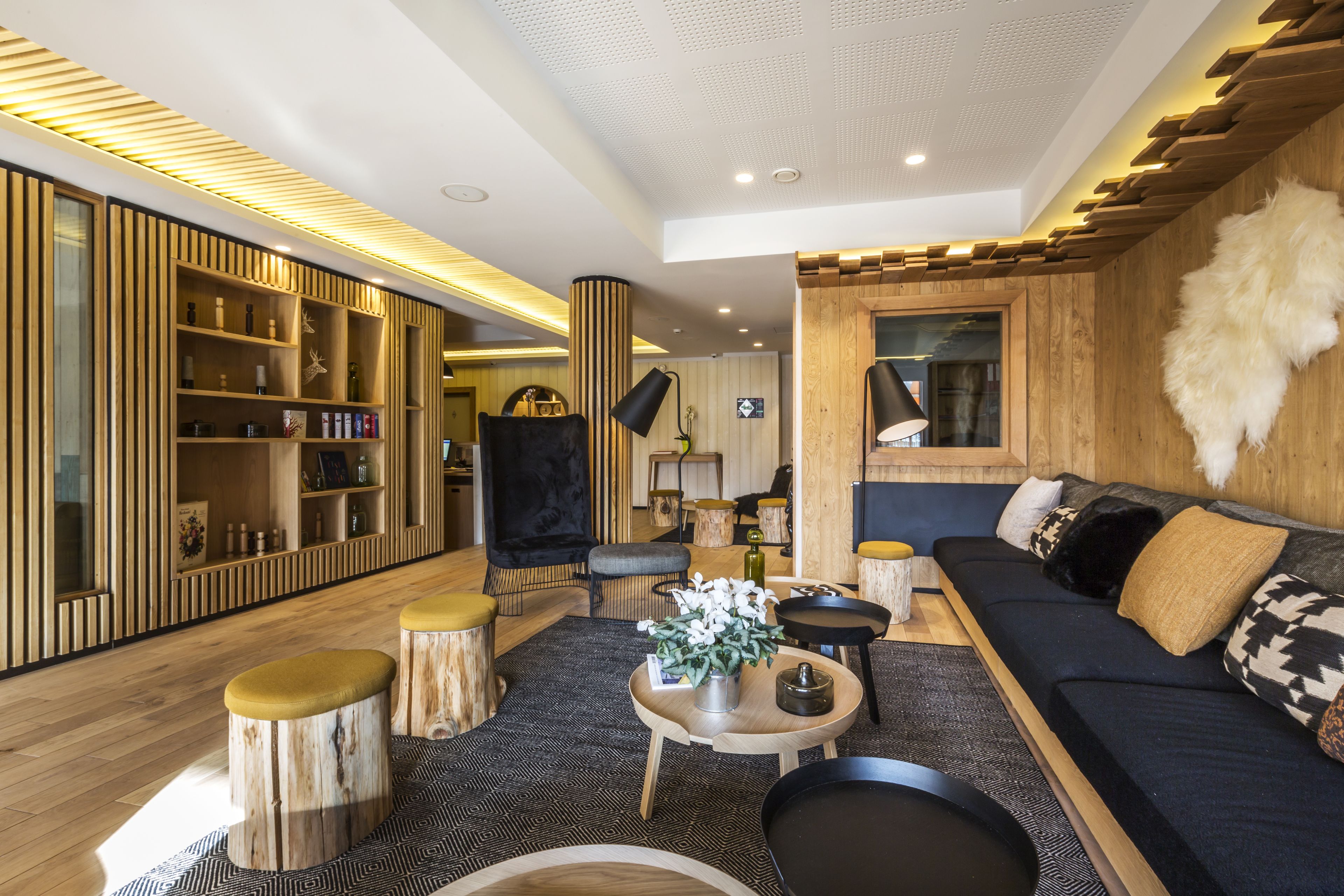Un salon moderne avec un canapé bleu foncé, des éléments décoratifs en bois et un tapis aux motifs noir et blanc.
