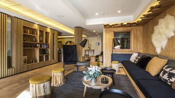 Un salon moderne avec un canapé bleu foncé, des éléments décoratifs en bois et un tapis aux motifs noir et blanc.