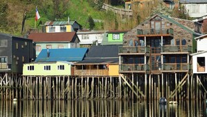 Una proprietà sul lungomare con palafitte di legno, edifici colorati e una bandiera.