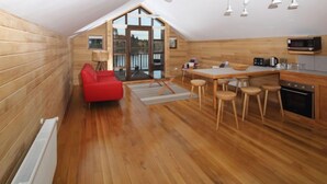 Una cucina moderna con pavimento in legno, una sedia rossa e un'area pranzo con sgabelli.