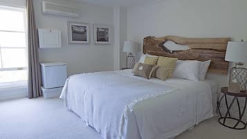 Une chambre à coucher avec un grand lit, une tête de lit en bois, une table de chevet avec une lampe et une fenêtre avec des rideaux.