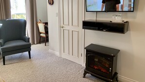 A living room with a television, a fireplace, a chair, and a door.