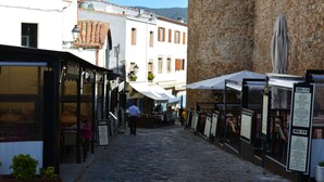 A narrow cobblestone street lined with buildings, some with outdoor seating and menus displayed. - Apartamento Puerto Rico 39 (Tossa de Mar)