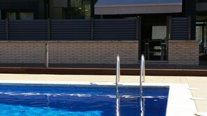 A swimming pool with a clear blue water surface, surrounded by a tiled edge and a brick wall. - Apartamento Puerto Rico 39 (Tossa de Mar)