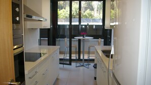 A modern kitchen with a dining area, featuring a large window, a dining table with chairs, and a view of the outdoors. - Apartamento Puerto Rico 39 (Tossa de Mar)