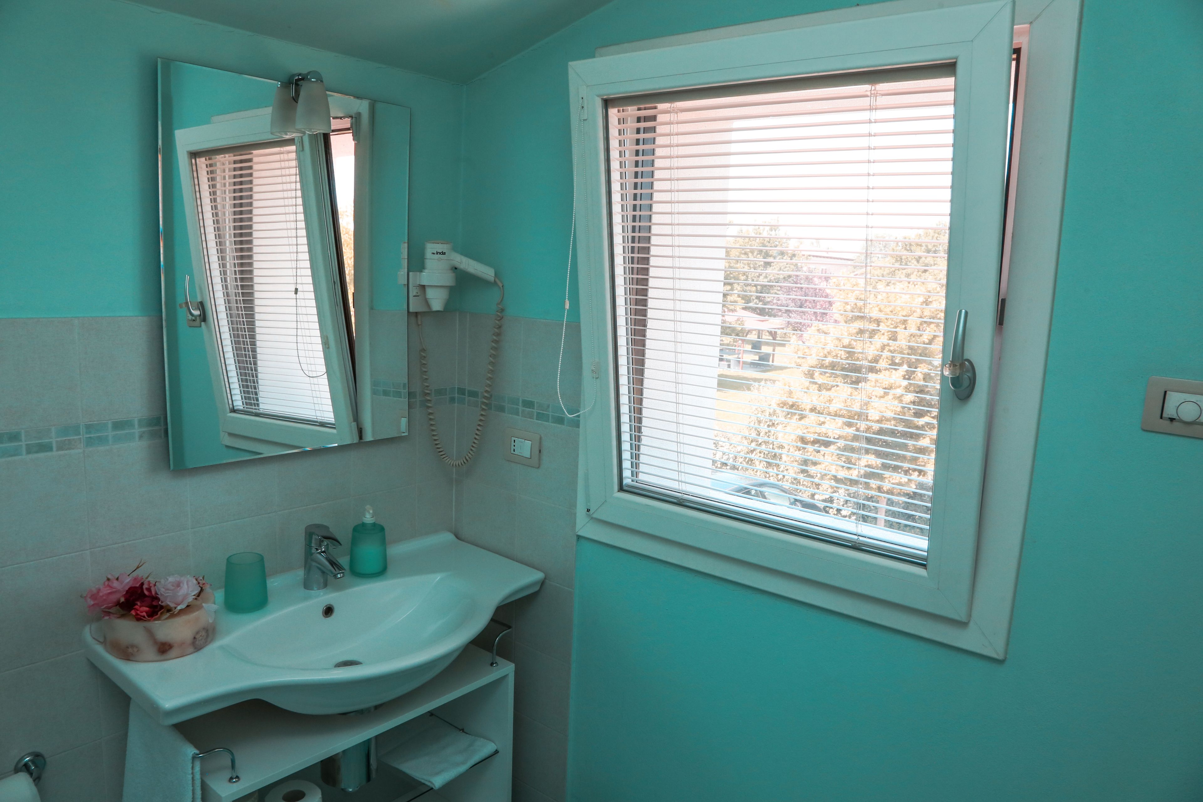 Une salle de bain avec un lavabo, un miroir et une fenêtre.