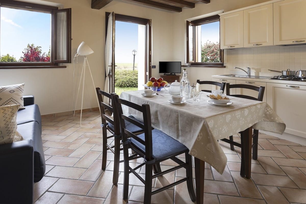 A dining area with a table set for two, a sofa, and a TV in the background.