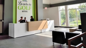Un espace d’accueil au design moderne, comprenant un comptoir d’accueil, un coin salon et de grandes fenêtres laissant entrer la lumière naturelle.
