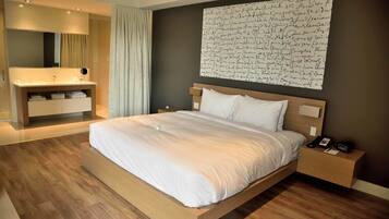 Una habitación de hotel moderna con una cama de madera, un tocador empotrado con espejo y una obra de arte grande colgada en la pared.