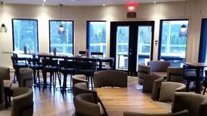 Une salle de conférence dotée d’une grande table et de nombreuses chaises, de grandes fenêtres donnant sur la verdure et d’une porte avec un panneau indiquant la sortie.