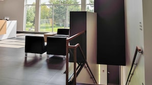 Un intérieur moderne avec un plafond haut, un éclairage encastré et de grandes fenêtres offrant une vue sur la verdure.