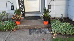 A house entrance with a 'WELCOME' sign, a mailbox, and two potted plants. - Kalmia Cottage (Junction City)