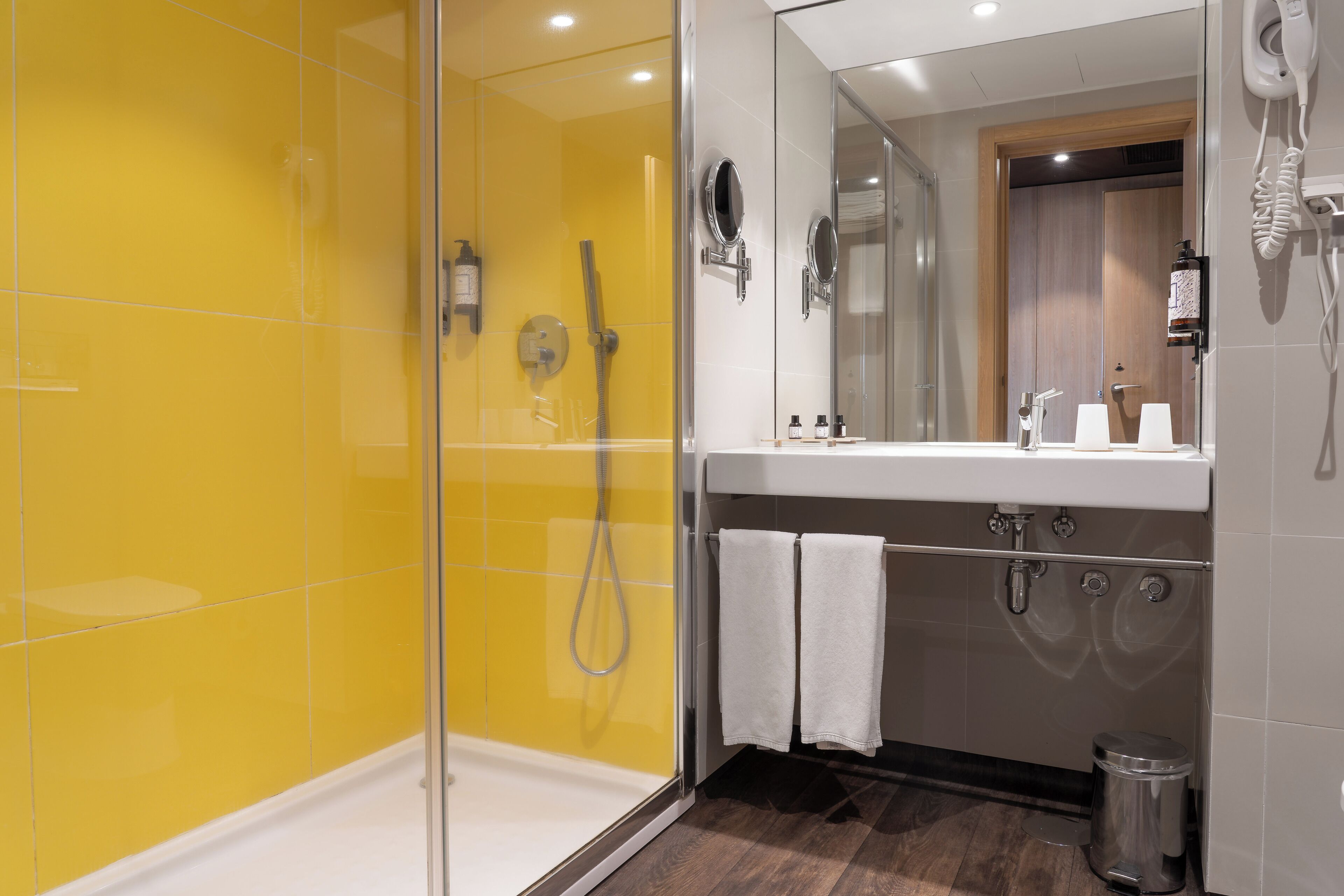 Une salle de bain moderne avec une douche à parois de verre, un lavabo blanc et un miroir au-dessus.