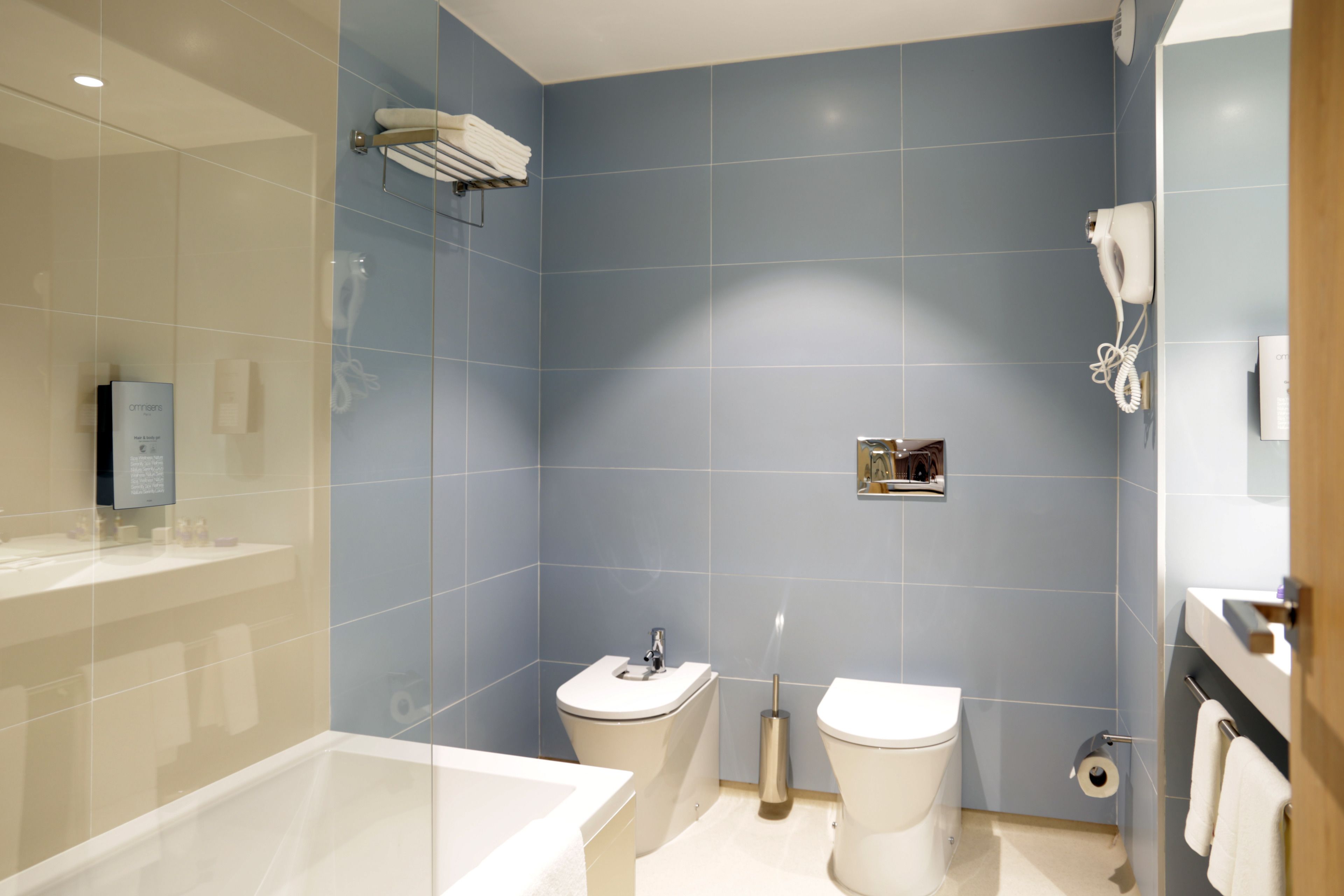 A modern bathroom with a bathtub, toilet, and bidet.