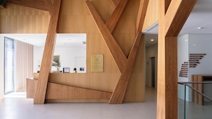 A modern reception area with wooden accents, a glass staircase, and directional signage.