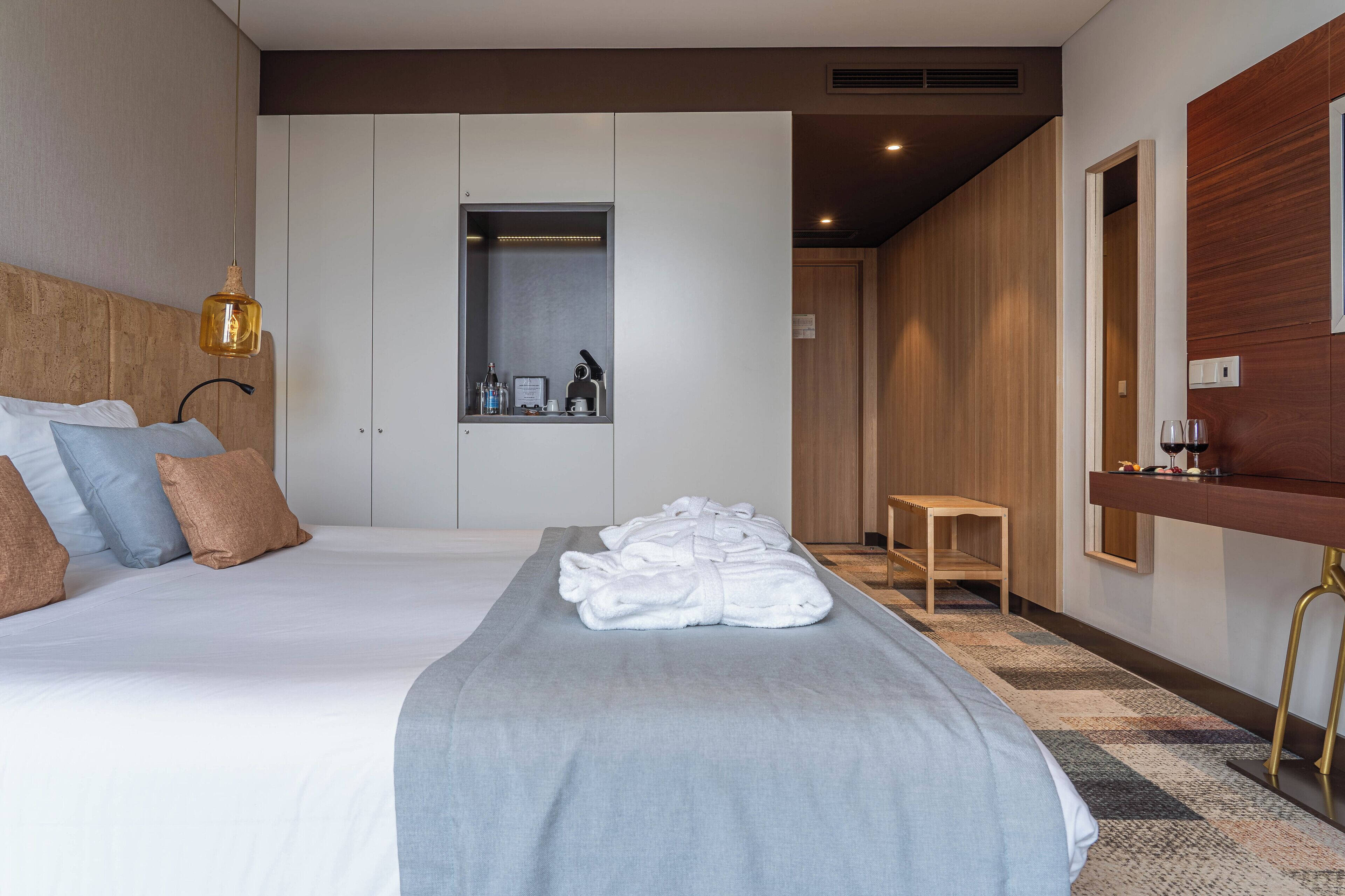 Ein Hotelzimmer mit einem großen Bett, einem Nachttisch, einem Spiegel und einem Kleiderschrank.