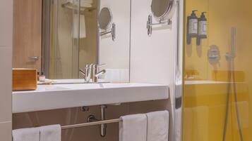 A modern bathroom with a glass-enclosed shower, a large mirror, and a wooden vanity.