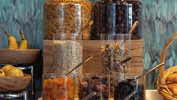 A variety of food items displayed in clear containers, including grains, nuts, and dried fruits, arranged on a wooden surface with a decorative background.