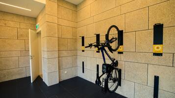 Un moderno vestíbulo de hotel con un soporte para bicicletas en la pared, una puerta que da a una habitación y un suelo limpio de baldosas.