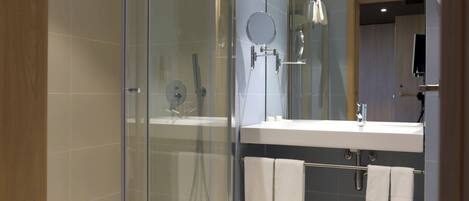 A modern bathroom with a glass-enclosed shower, a white sink, and a mirror above it.