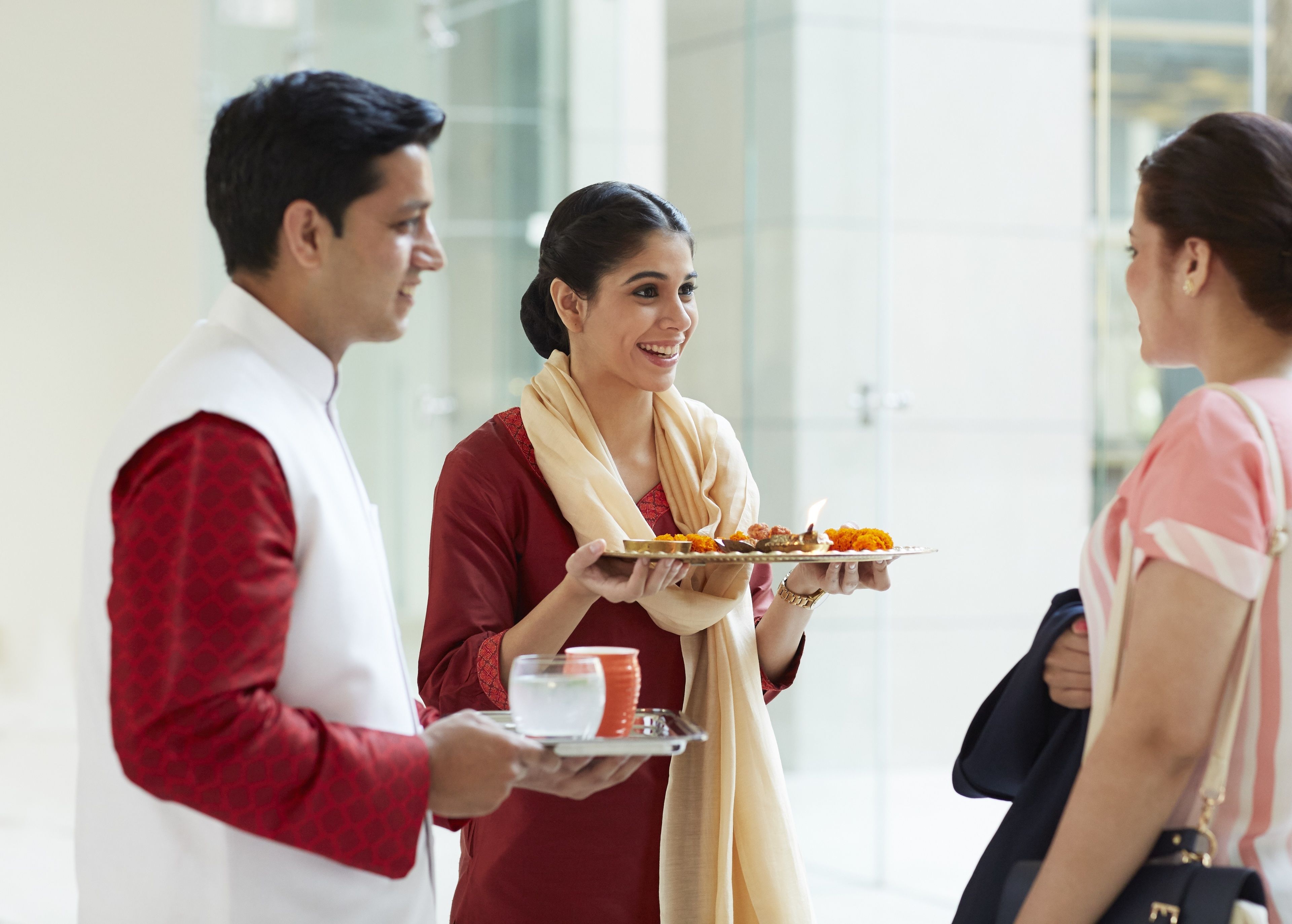 A person holding a tray with food and a cup, standing in a modern indoor setting with glass walls.