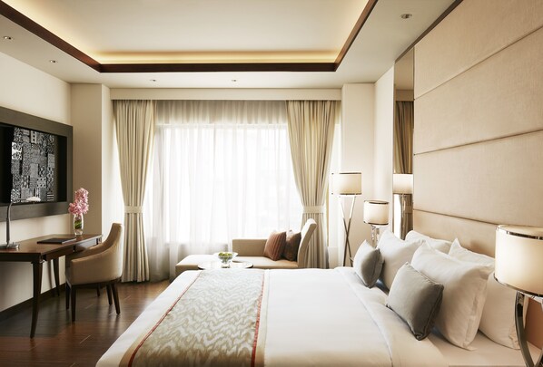 Une chambre d’hôtel avec un grand lit, un bureau, une chaise, une télévision et une fenêtre avec des rideaux.