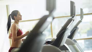Eine Frau läuft auf einem Laufband in einem Fitnessstudio mit großen Fenstern.