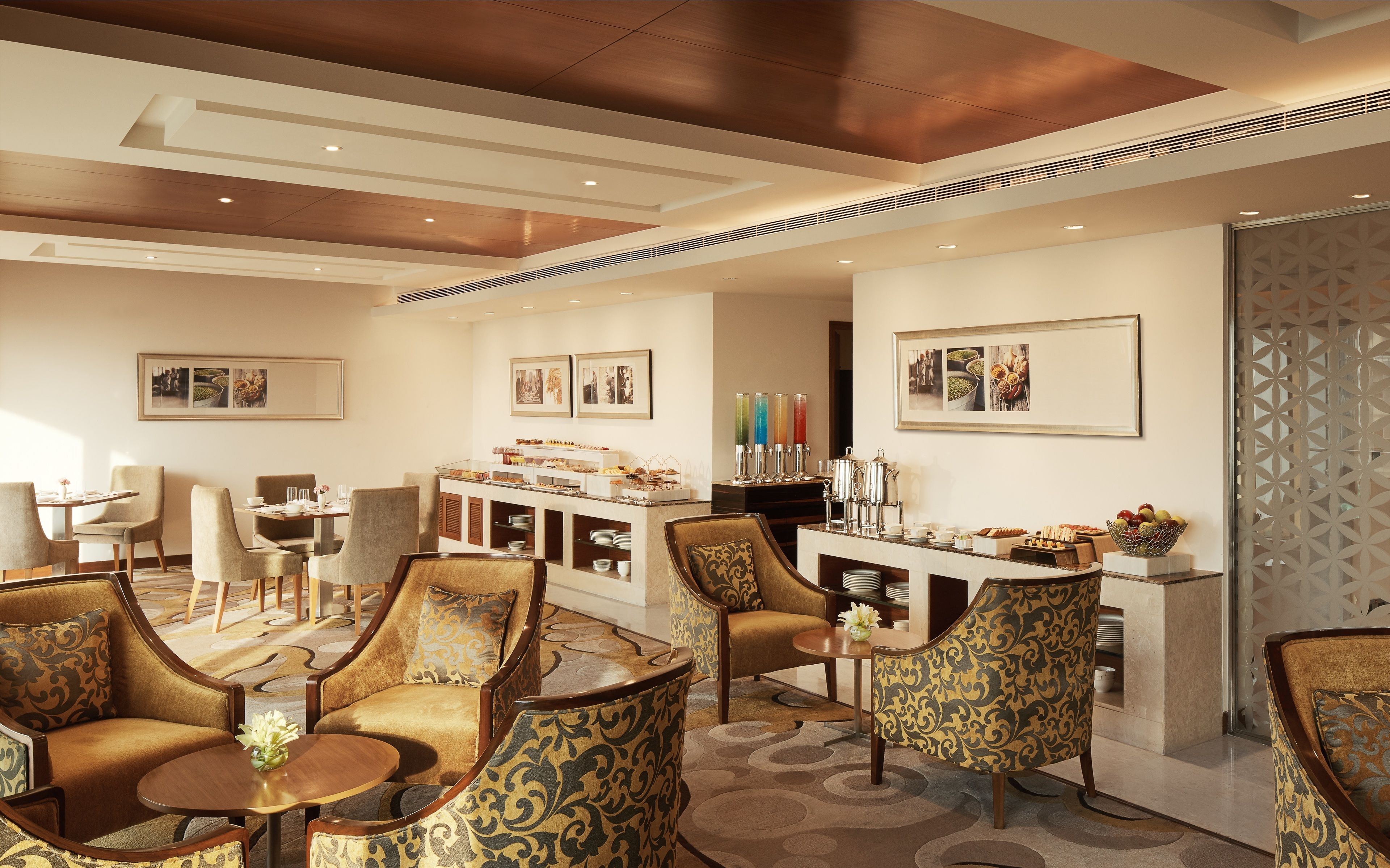 Een ruime lounge met zachte zitplaatsen, een buffet en kunstwerken aan de muur.