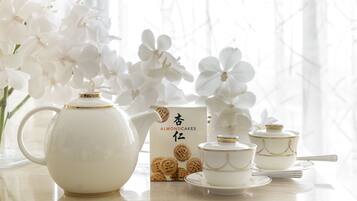 A tea set with a teapot, cups, and saucers, accompanied by a box of almond cakes.