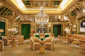 A luxurious interior with a grand chandelier, plush seating, and a patterned floor.