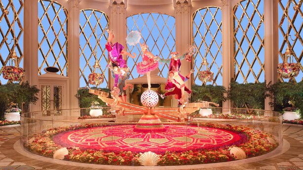 A grand atrium with a central floral arrangement, ornate columns, and a large decorative globe. - Wynn Palace (Cotai)