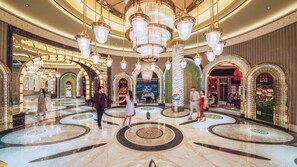 A luxurious hotel lobby with marble floors, ornate chandeliers, and multiple dining areas. - Wynn Palace (Cotai)