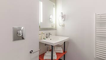 Ein modernes Badezimmer mit Waschbecken, Spiegel, Föhn und Handtuchhalter.
