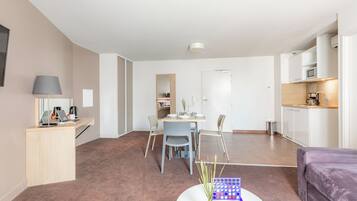 Un salon moderne comprenant un coin repas, une cuisine et un petit espace bureau.