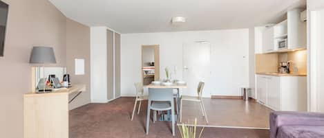Una sala de estar moderna con comedor, cocina y un pequeño espacio de oficina.
