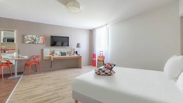 Habitación de hotel moderna con cama, escritorio, silla, televisión y vistas al exterior.