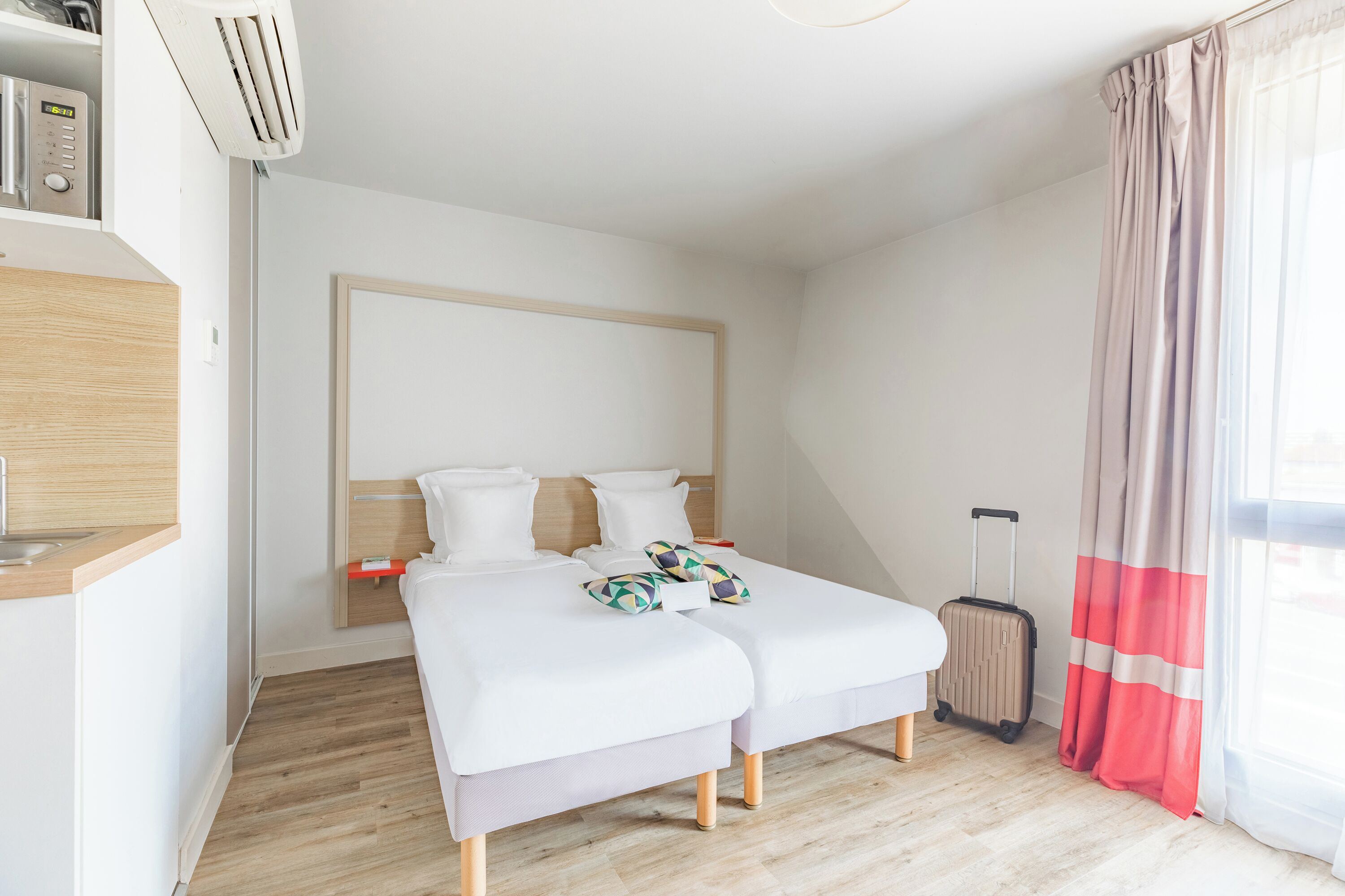 Une chambre d’hôtel moderne avec un lit, un petit bureau et une valise.