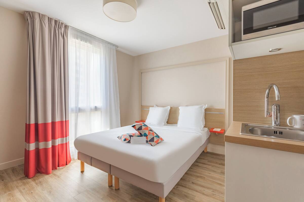 Een hotelkamer met een bed, nachtkastje, wastafel en een magnetron.