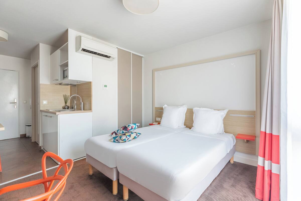 Een hotelkamer met een bed, een kleine keuken, een stoel en een badkamer.