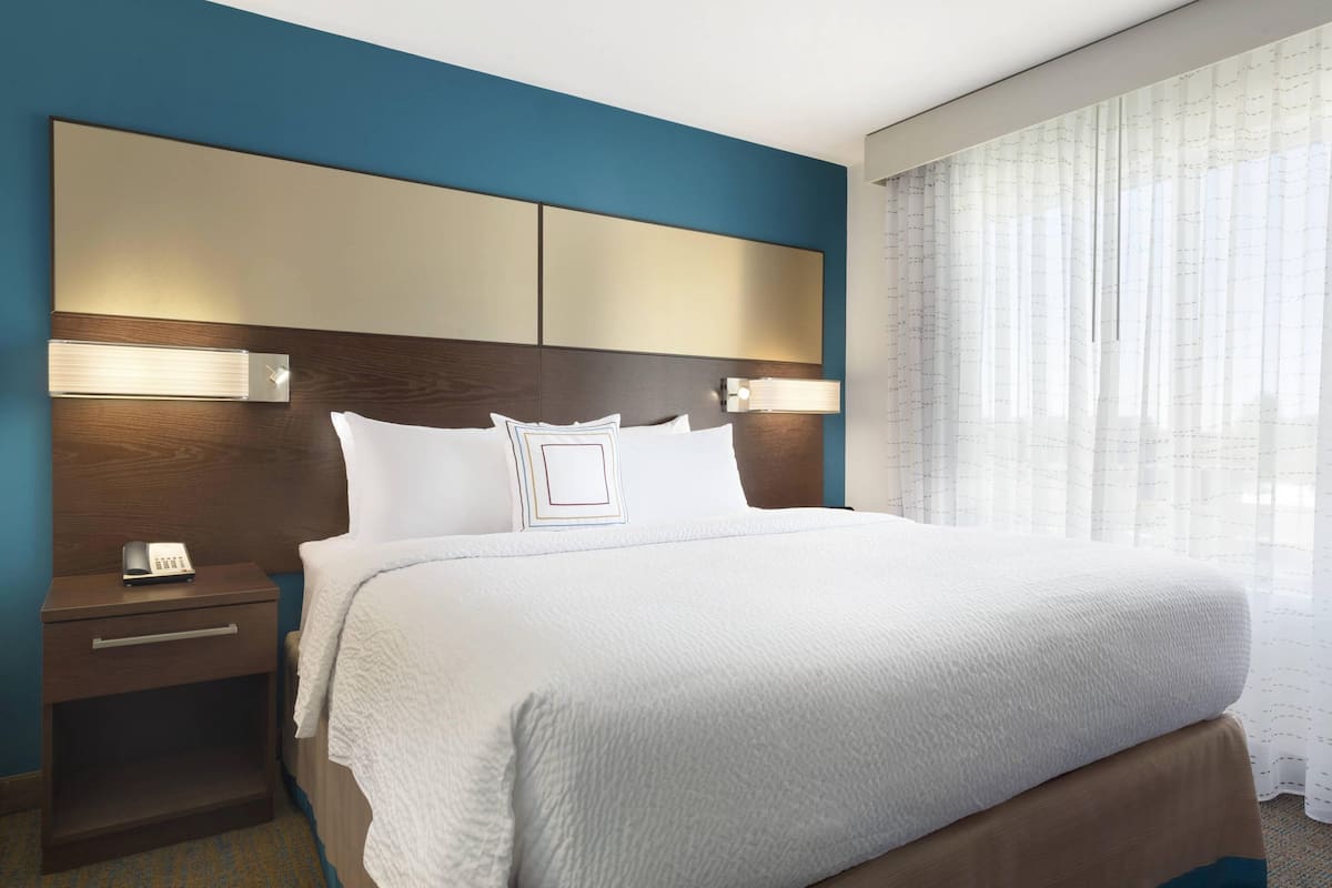 Ein Hotelzimmer mit einem großen Bett, einem Nachttisch mit Telefon und einem Kopfteil mit integrierter Beleuchtung.