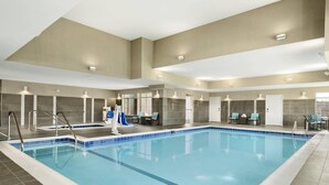 Una amplia piscina interior con suelo y paredes de azulejos, equipada con varios vestuarios y zonas de estar.
