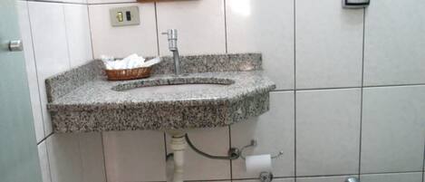 Un baño con lavamanos de granito, un espejo, un inodoro y un cubo de basura.