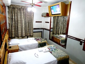 Une chambre d’hôtel avec deux lits, un téléviseur fixé au mur et un miroir qui reflète une partie de la pièce.
