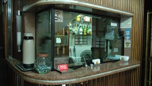 A hotel reception area with a glass partition, a Wi-Fi sign, a minibar, and a small counter with a 'BBB' rating sign. - Hotel PC (São Paulo)