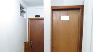 A hallway with a wooden door and a tiled floor. - Hotel PC (São Paulo)