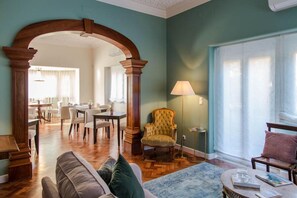 Un vaste salon agrémenté d’une arche en bois, d’un fauteuil moelleux, d’une table basse et, au fond, d’un coin repas.